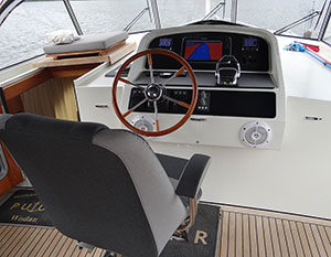 Steuerstand der Linssen 40.9, weißes Cockpit mit Holzsteuerrad und schwarzem Instrumentenboard