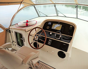 Steuerstand der Linssen 40.0, weißes Cockpit mit Holzsteuerrad, schwarzem Instrumentenboard und Rettungsring auf dem Niedergang